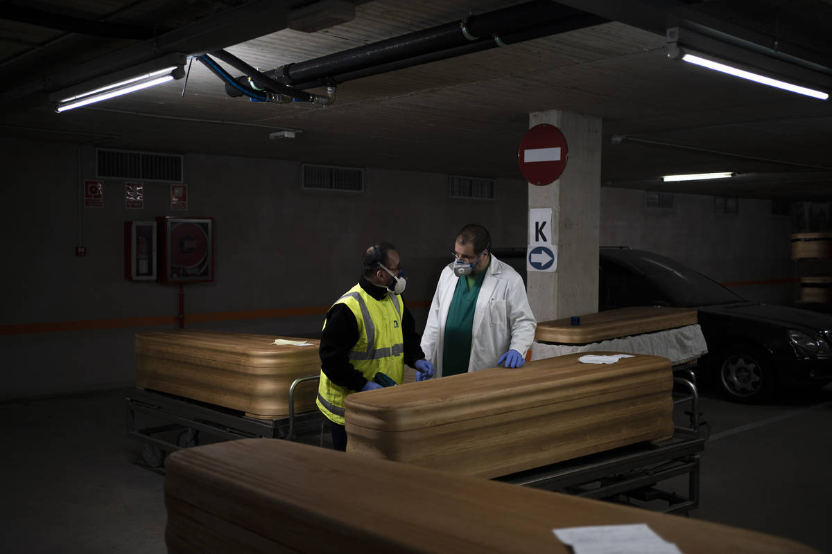 In this April 14, 2020, photo, head mortician Jordi Fernandez, right, speaks to a colleague aft ...