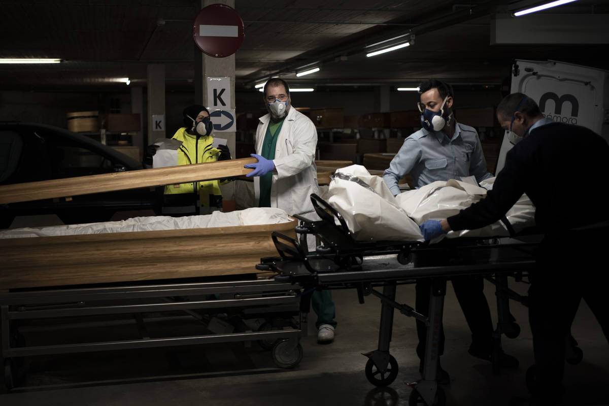 In this April 14, 2020, photo, head mortician Jordi Fernandez, center, closes the coffin of a C ...
