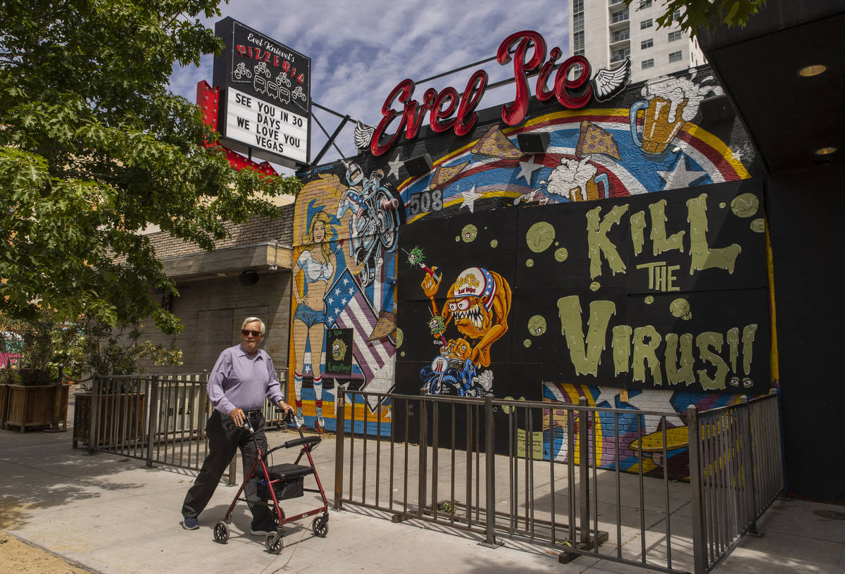 A pedestrian walks past a closed Evel Pie on an empty Fremont Street in Downtown Las Vegas duri ...