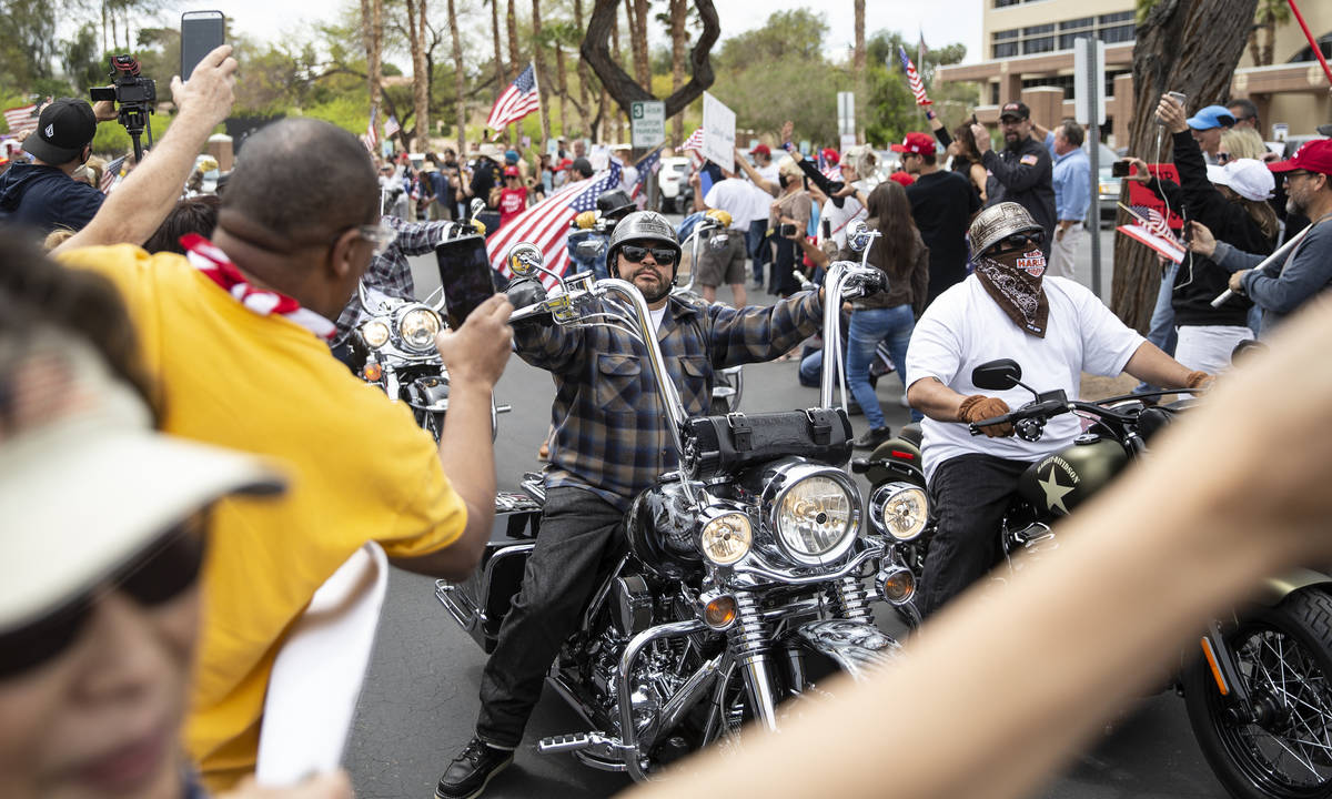 A large group of bikers drive through a row of protesters during an event organized by Reopen N ...