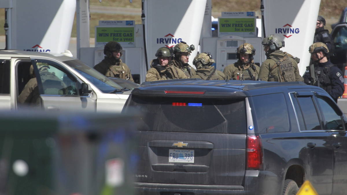 Royal Canadian Mounted Police officers prepare to take a person into custody at a gas station i ...