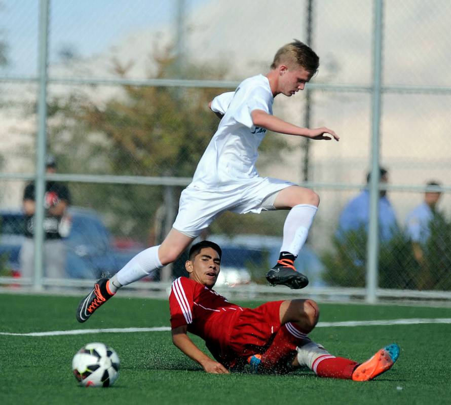 Palo Verde striker Presten Manthey jumps over the slide tackle of Valley defender Steve Favela ...