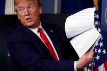 President Donald Trump holds up papers as he speaks about the coronavirus in the James Brady Pr ...
