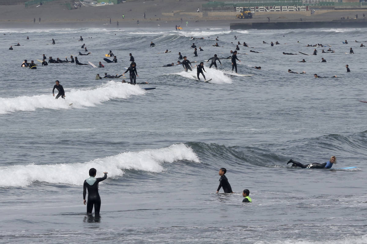 People go surfing off Katase Kaigan beach in Fujisawa, near Tokyo, Tuesday, April 21, 2020. Ja ...