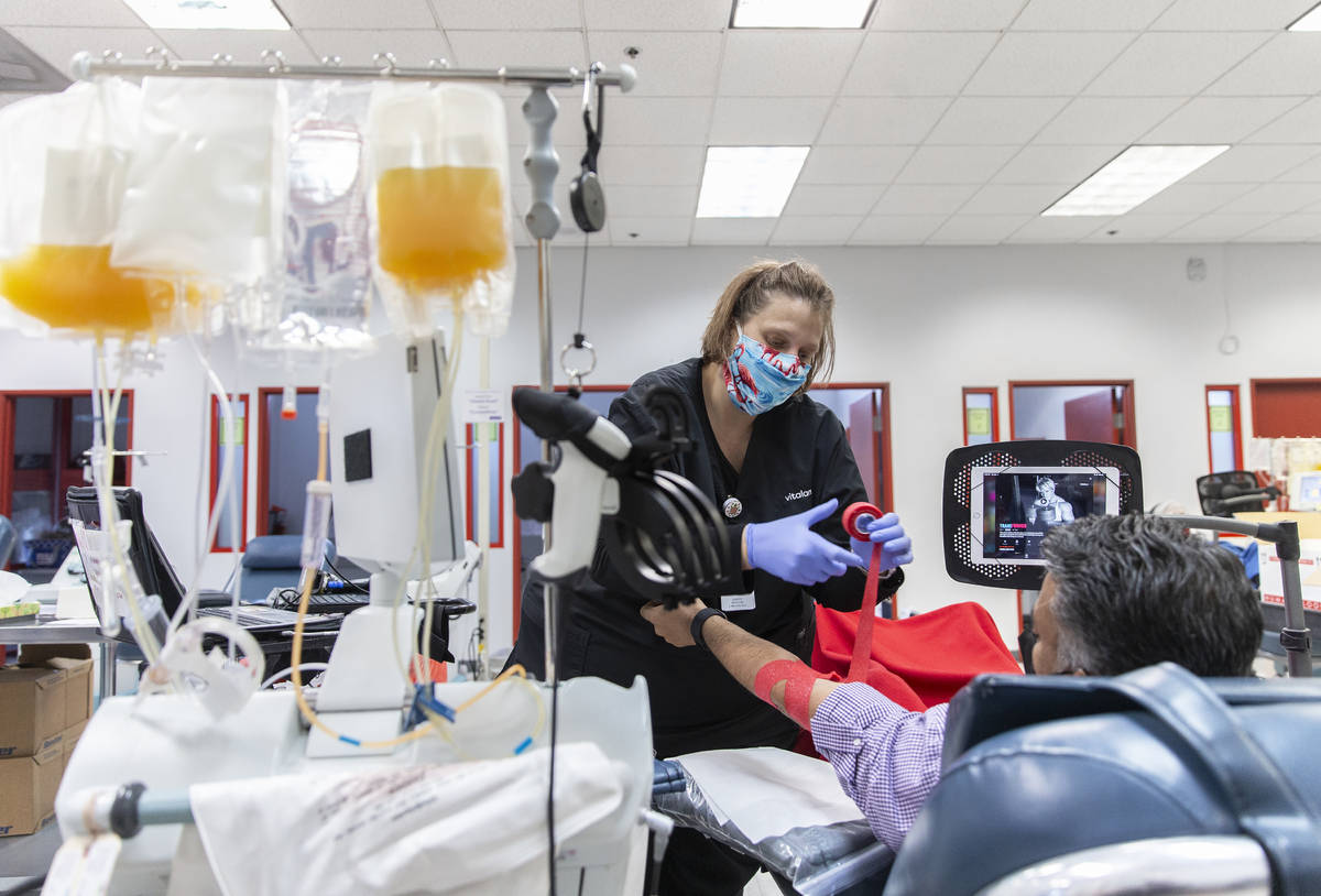 Phlebotomist Courtney Gaudette, left, wraps the arm of a man that donated plasma at Vitalant on ...