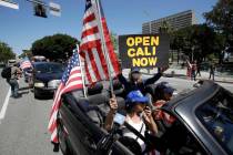 Protesters drive by in a convertible car during a rally calling for an end to California Gov. G ...