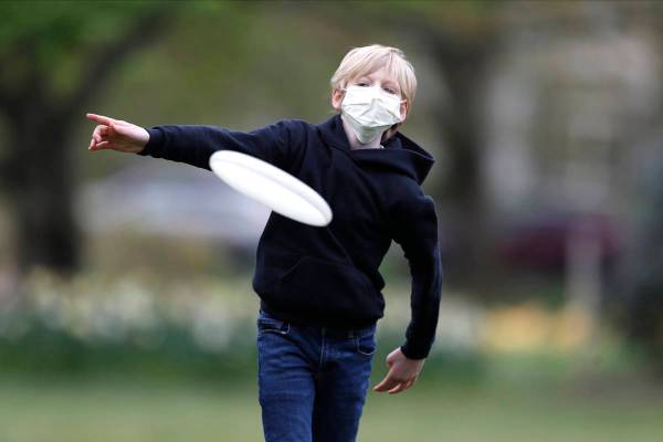 Shawn Cotter, 11, wears a face mask as he throws a Frisbee while playing catch with his father ...