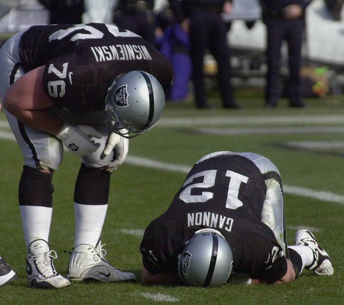 Oakland Raiders quarterback Rich Gannon (12) kneels in pain after being sacked by Baltimore Rav ...