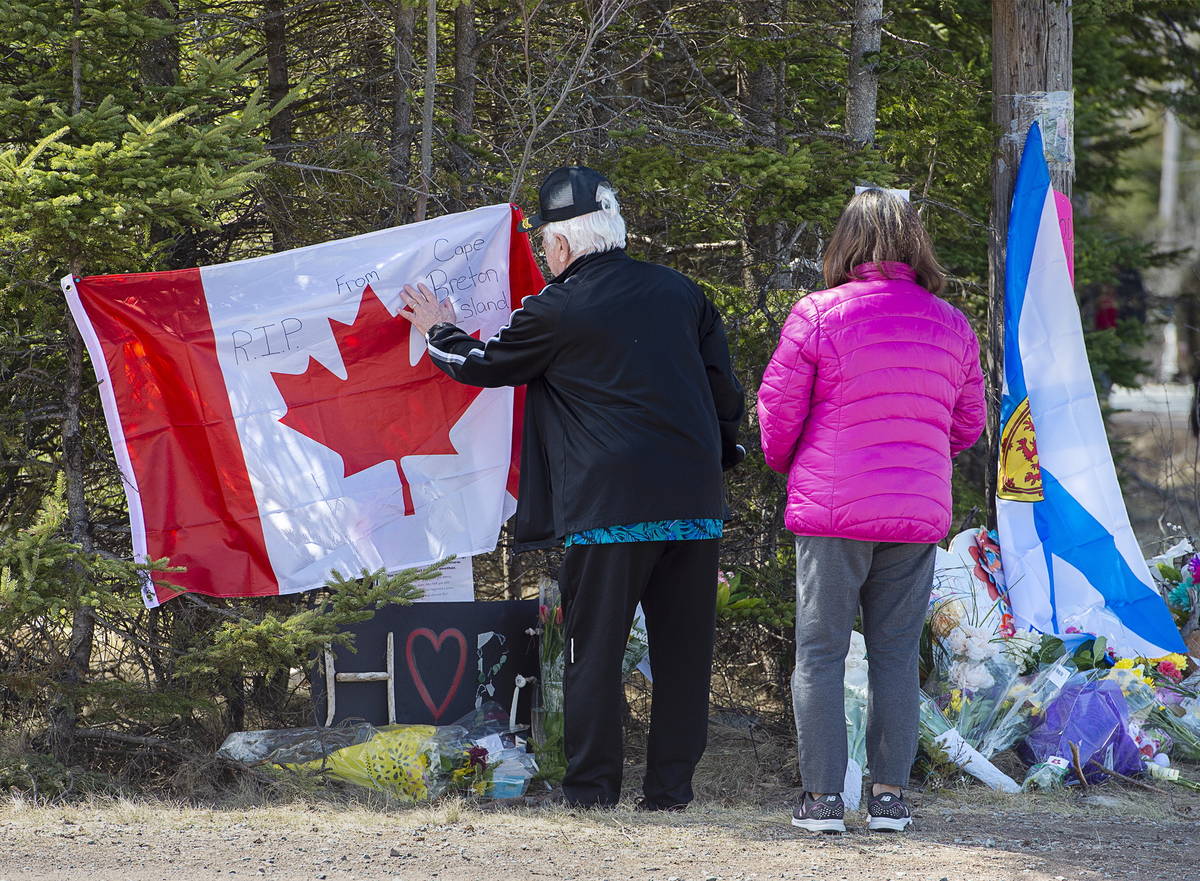 In this Wednesday, April 22, 2020, photo, a couple place a flag at a memorial in Portapique, No ...