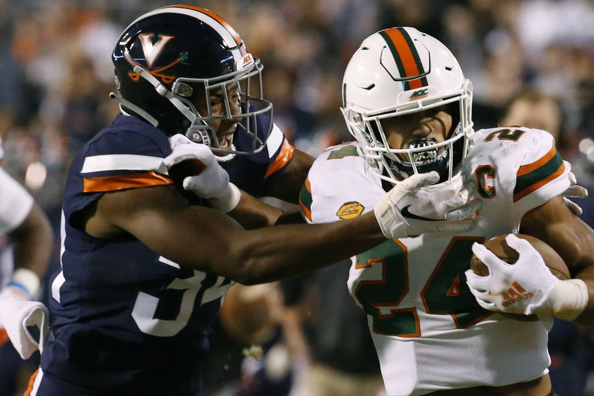Miami running back Travis Homer (24) pushes off Virginia cornerback Bryce Hall (34) during the ...