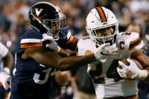 Miami running back Travis Homer (24) pushes off Virginia cornerback Bryce Hall (34) during the ...