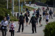 Catalan police officers patrol as families with their children walk along a boulevard in Barcel ...
