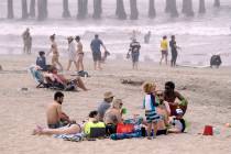 People sit on the beach Sunday, April 26, 2020, in Huntington Beach, Calif. (AP Photo/Marcio Jo ...