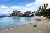 A couple rests on an empty section of Waikiki Beach in Honolulu on Saturday, March 28, 2020. (A ...