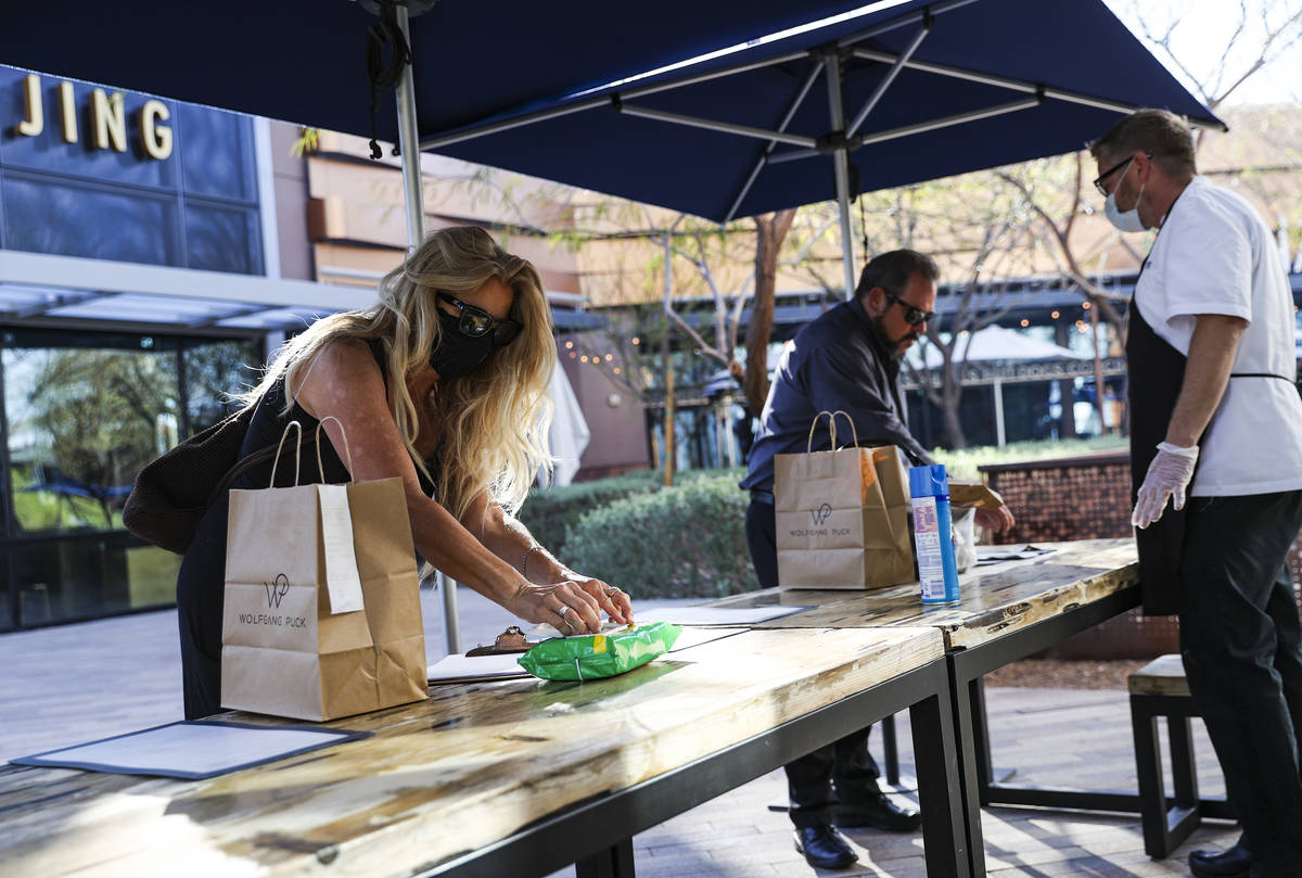Zetta Magliarditi, left, reaches for a sanitizing wipe while picking up food at Wolfgang Puck P ...