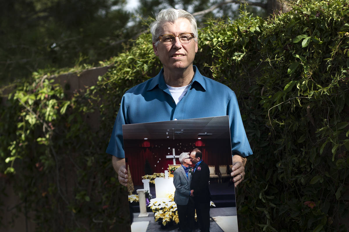 Richard Davis holds a photo of him and his husband Jeff Moore on their wedding day at his home ...
