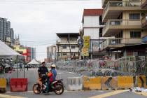 Malaysian Police check a motorcyclist next to barbed wire in the locked down area of Selayang B ...