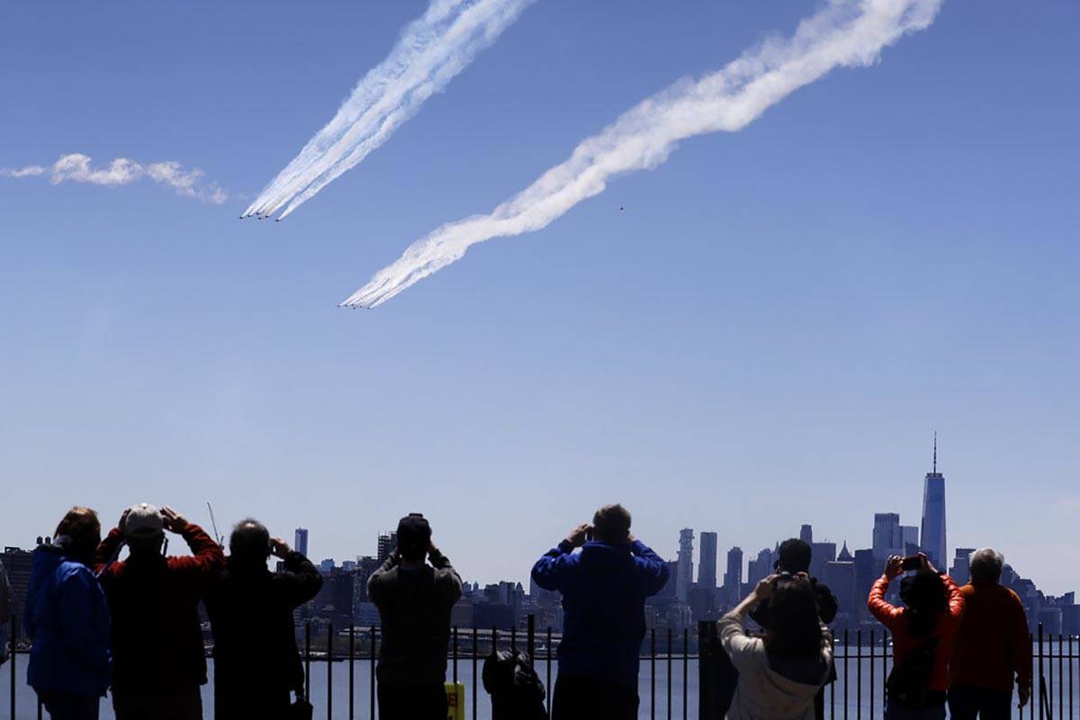 People watch as a formation of the Blue Angels and Thunderbirds flight teams pass in front of t ...