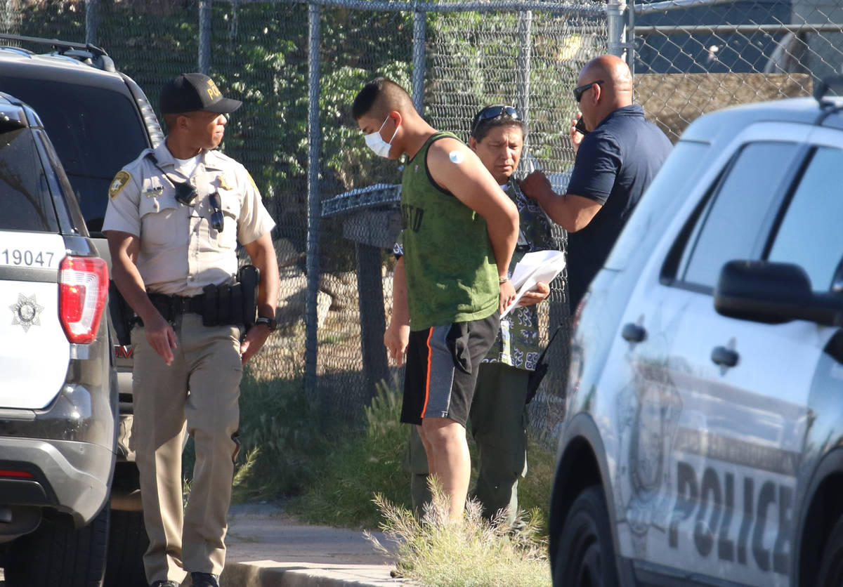 Las Vegas police officers escort a handcuffed man to an awaiting police vehicle near an apartme ...