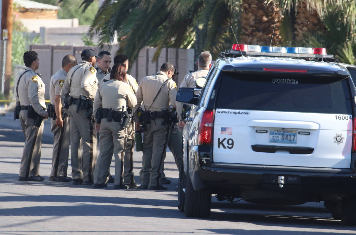 Las Vegas police officers lead a handcuffed man into an awaiting police vehicle near an apartme ...