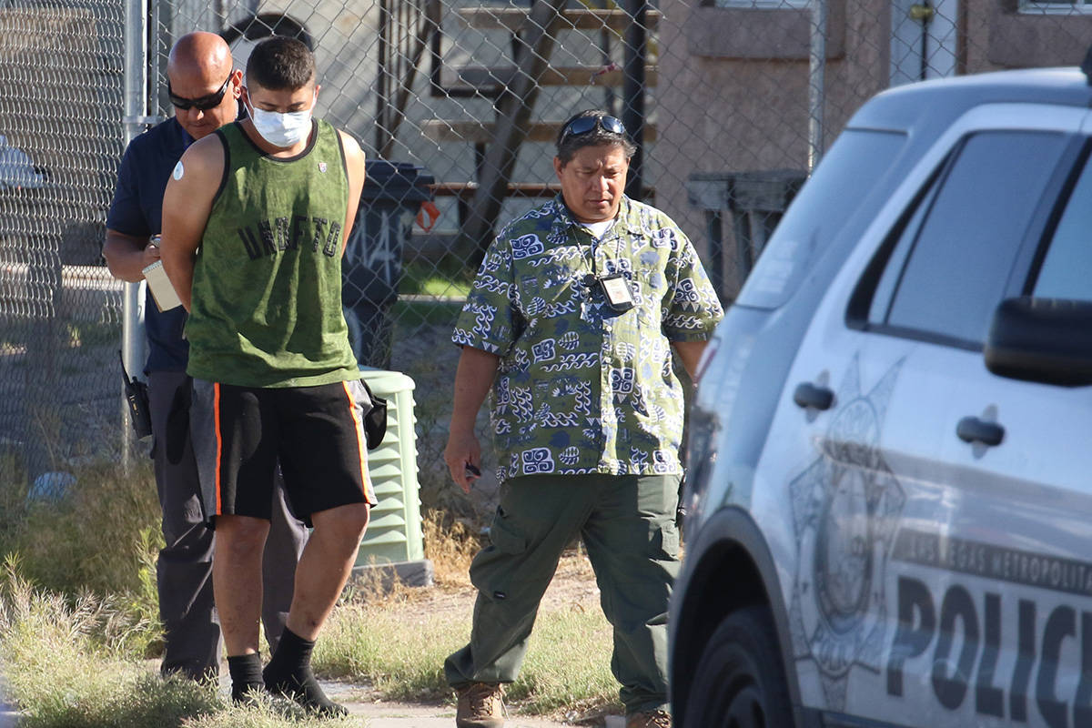 Las Vegas police officers lead a handcuffed man to an awaiting police vehicle near an apartment ...