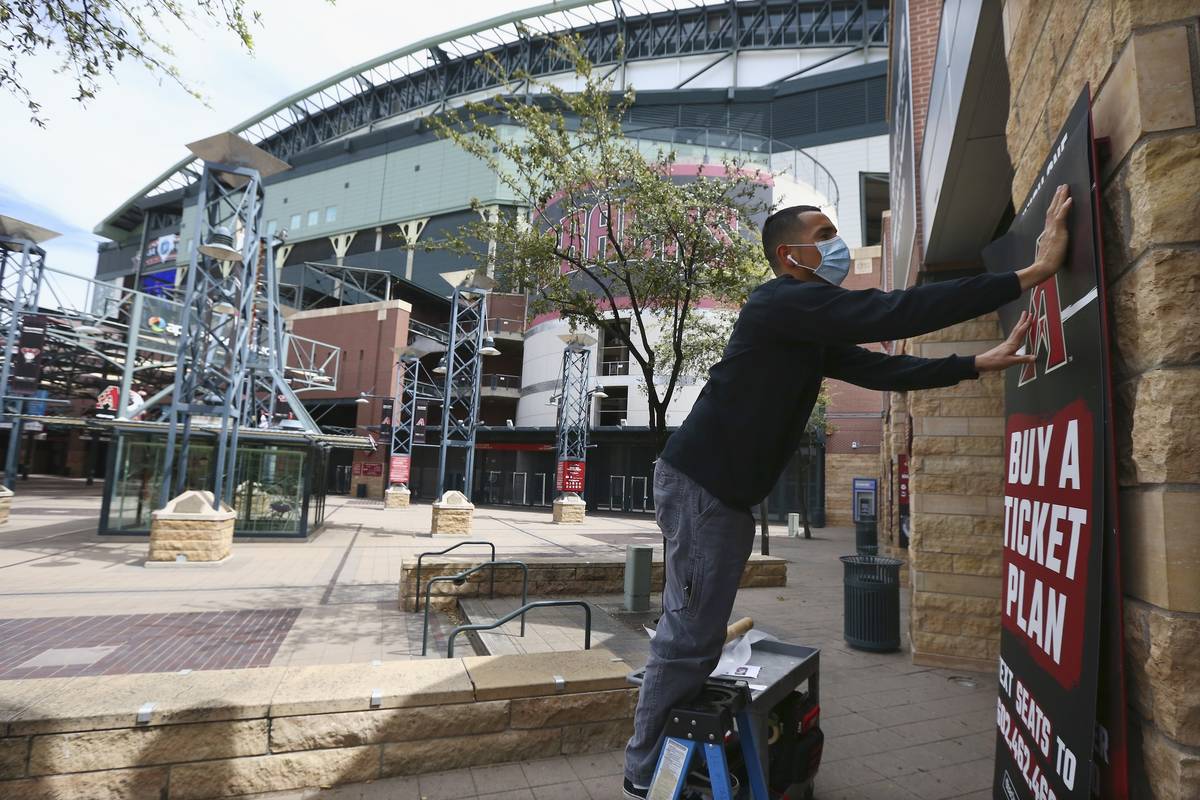 Joey Rodriguez, of Image Craft, installs an advertising banner in front of Chase Field Thursday ...