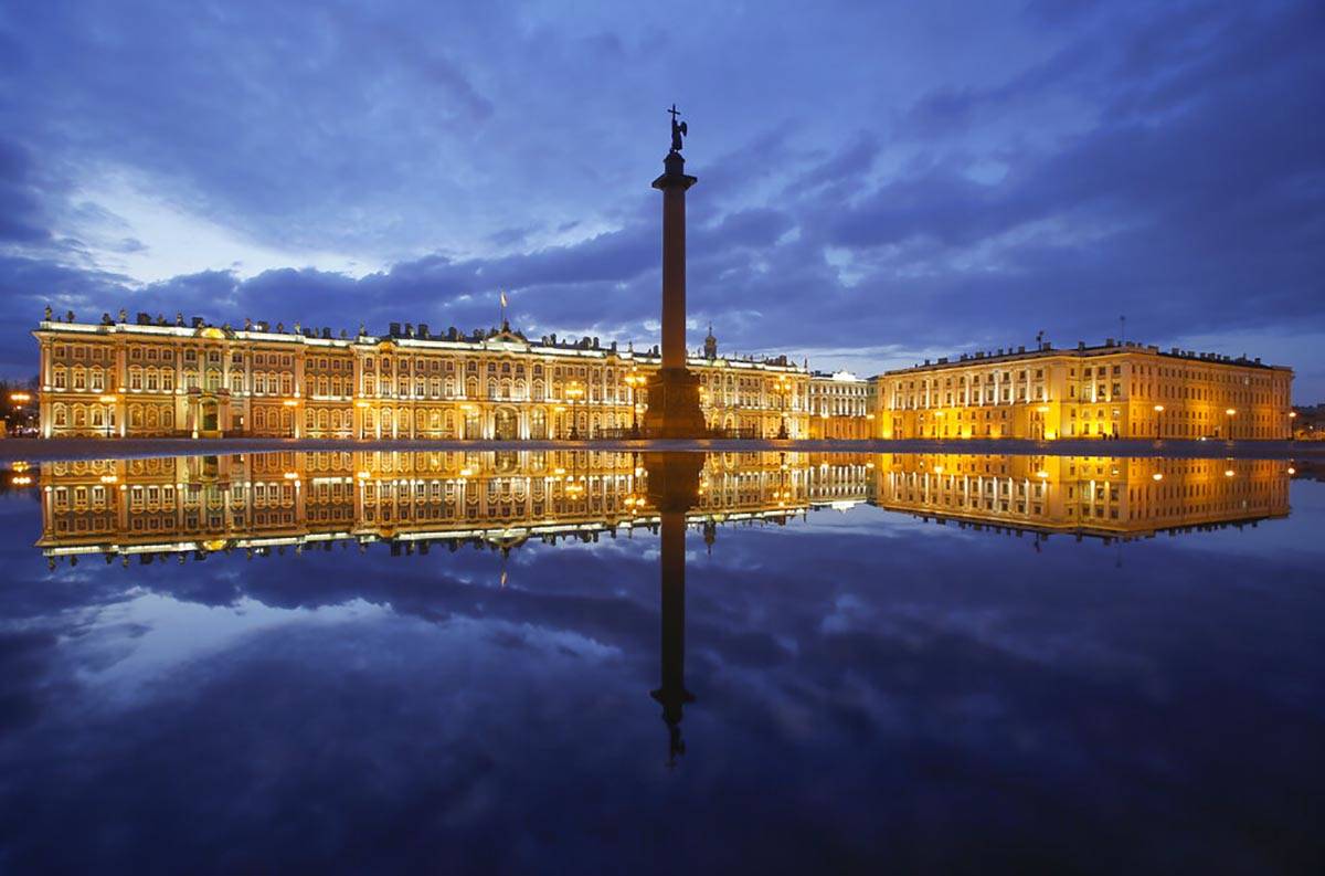 Winter Palace and the Alexander Column are reflected in a puddle after the rain at the Palace S ...