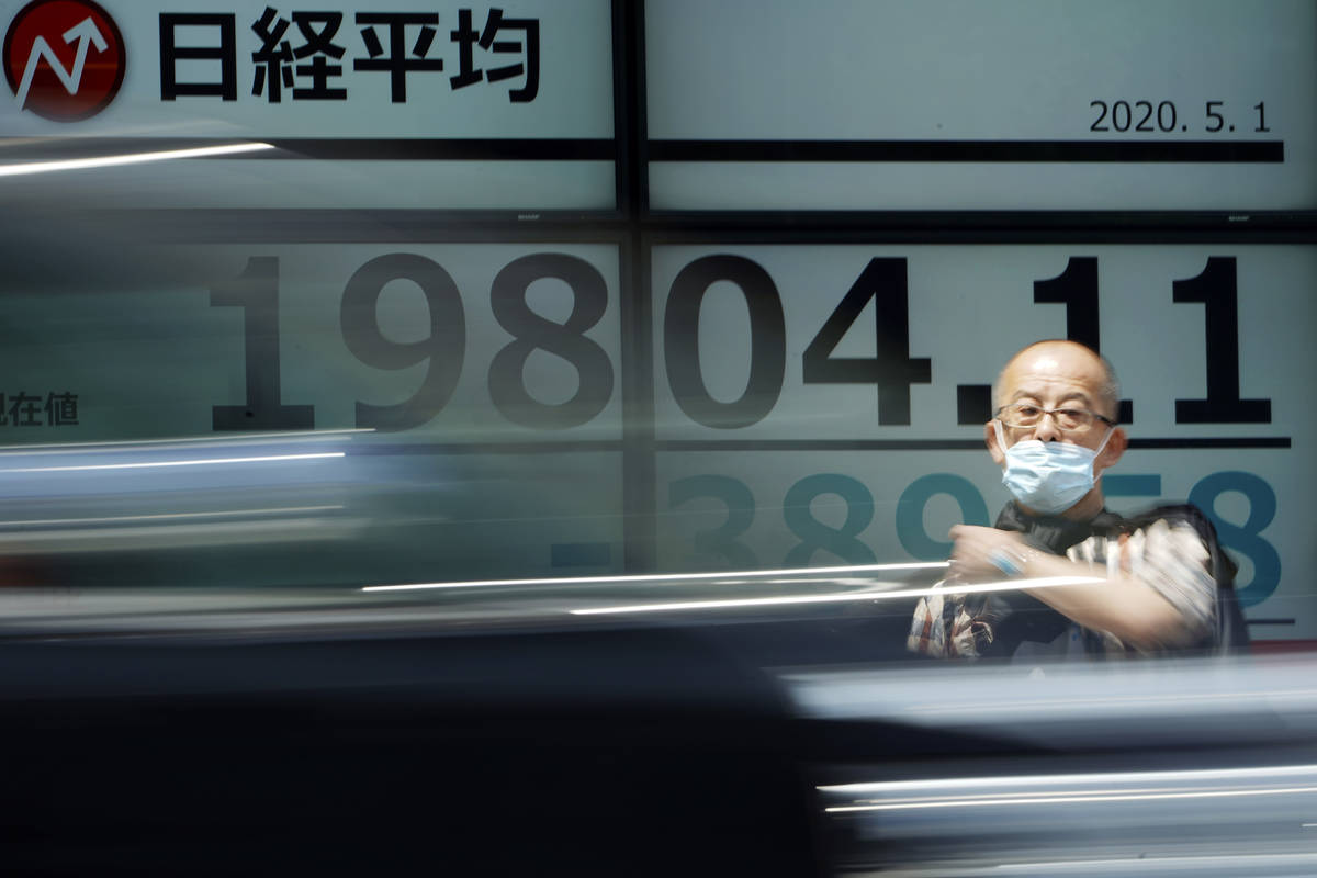 A man stands in front of an electronic stock board showing Japan's Nikkei 225 index at a securi ...