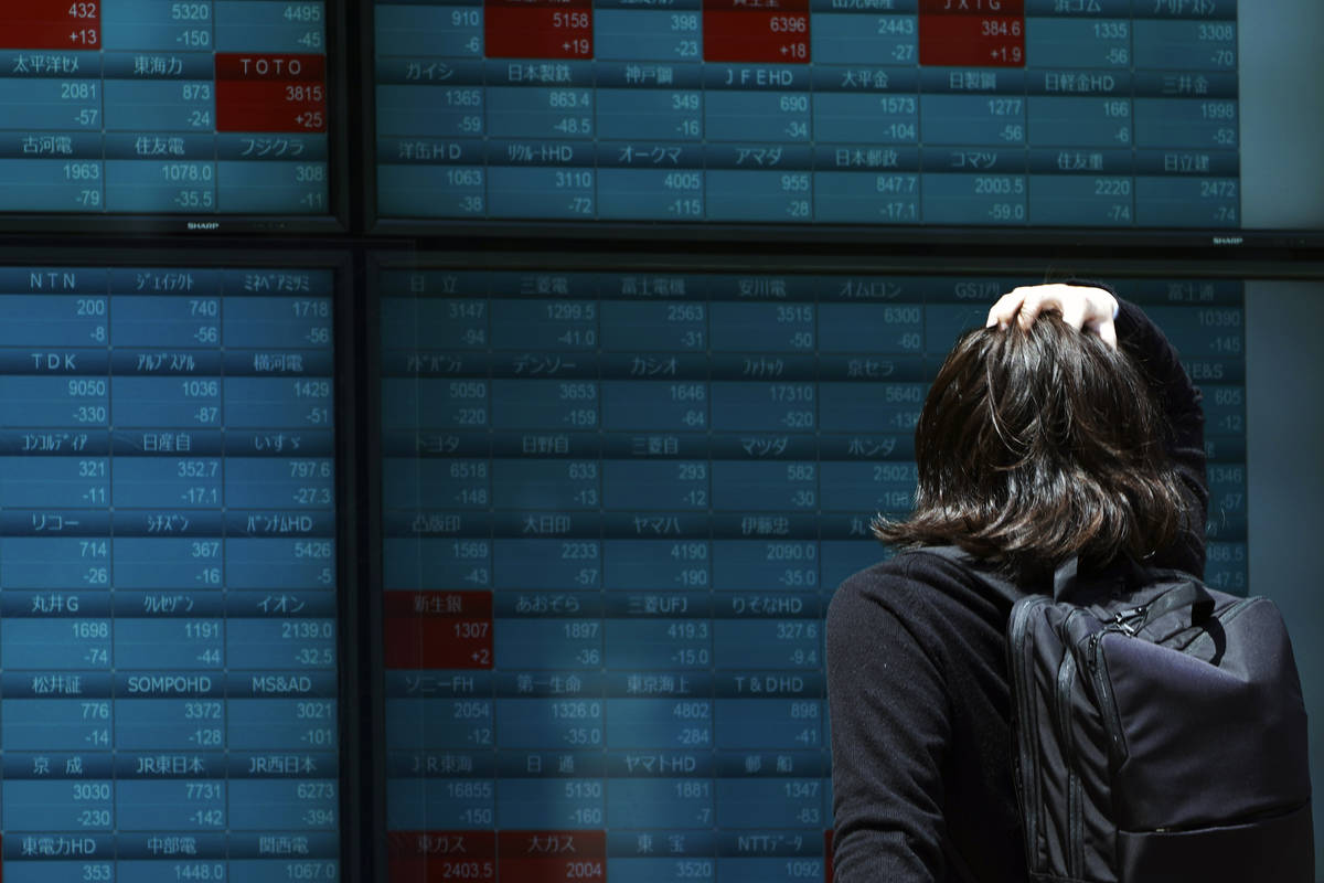 A man looks at an electronic stock board showing Japan's Nikkei 225 index at a securities firm ...
