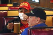 Cheers to You patron Clifford Pesheep, left, wears a mask before drinking his beer at the bar F ...