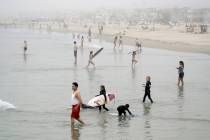 Swimmers and surfers wade in the water Sunday, April 26, 2020, in Newport Beach, Calif. (AP Pho ...