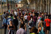 People exercise on a seafront promenade in this photo taken with a telephoto lens in Barcelona, ...