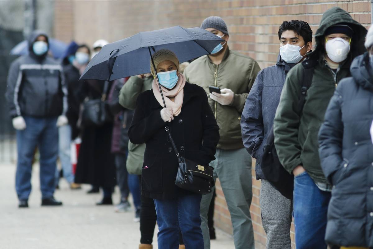 FILE - In this April 23, 2020, file photo, people line up at Gotham Health East New York, a COV ...
