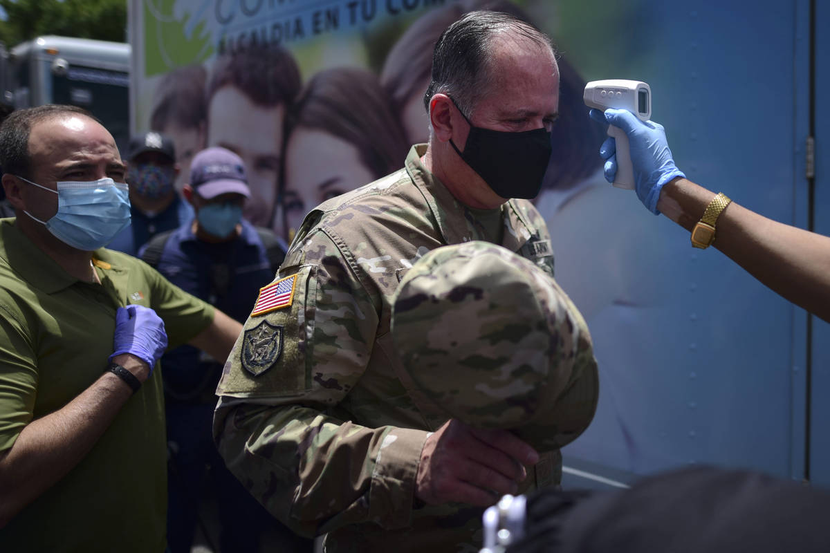A worker measures the temperature of Gen. Jose Reyes as a precaution against the spread of the ...