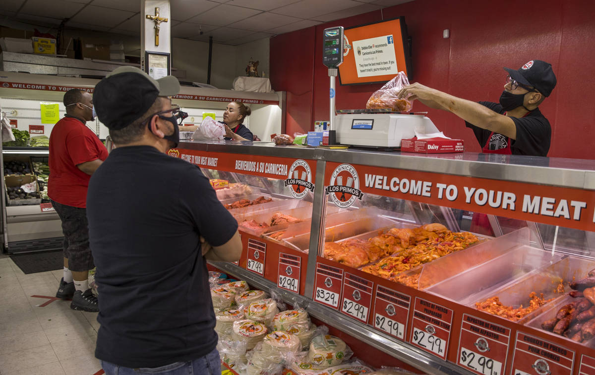 Javier Ramirez, right, weighs a meat order for a customer at the Los Primos Meat Market on Sund ...