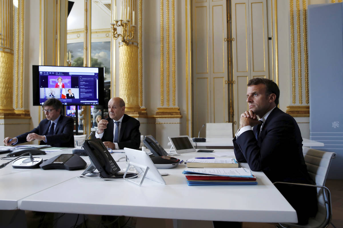 French President Emmanuel Macron, right, listens as he attends with French Foreign Minister Jea ...