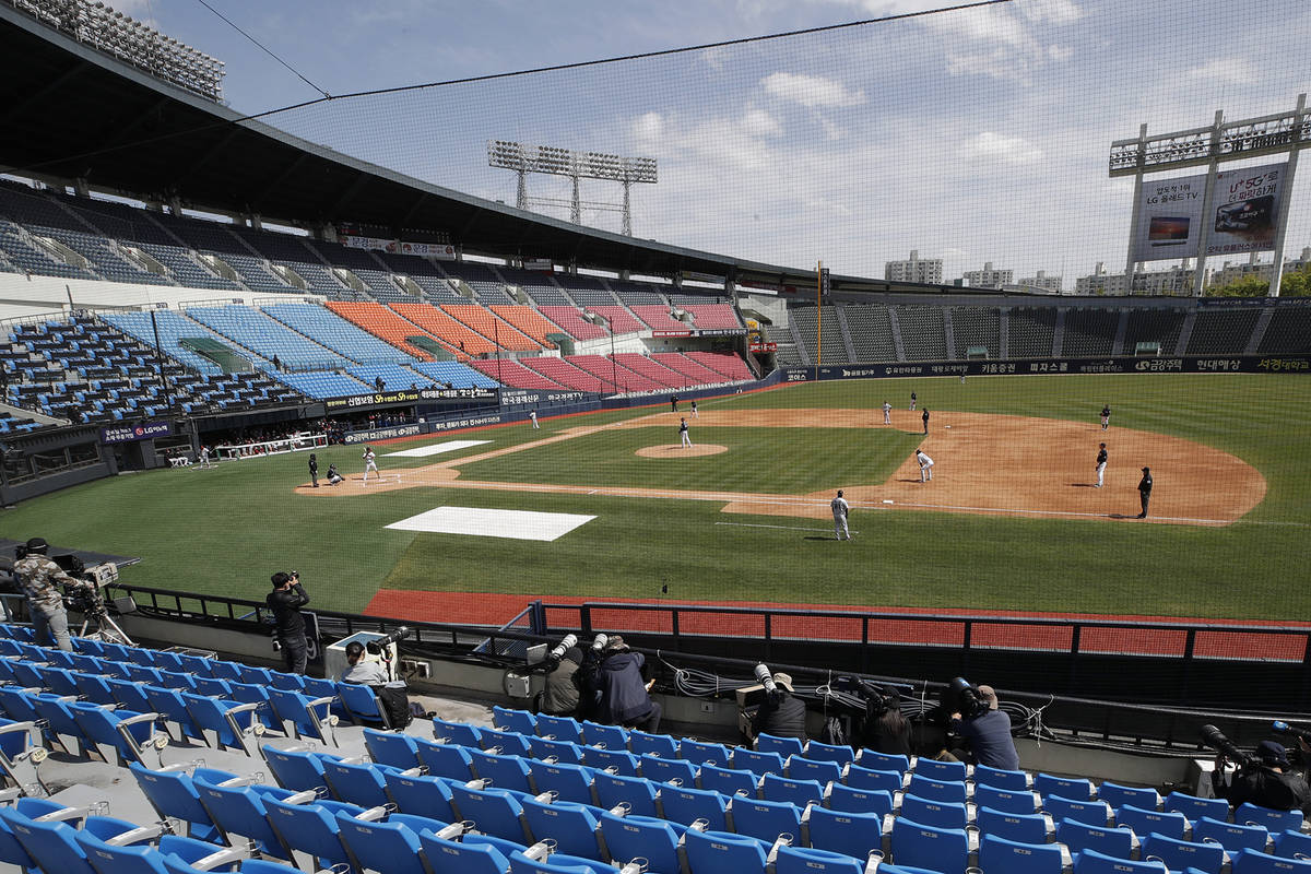 Photographers and TV camera work near empty seats during the pre-season baseball game between D ...