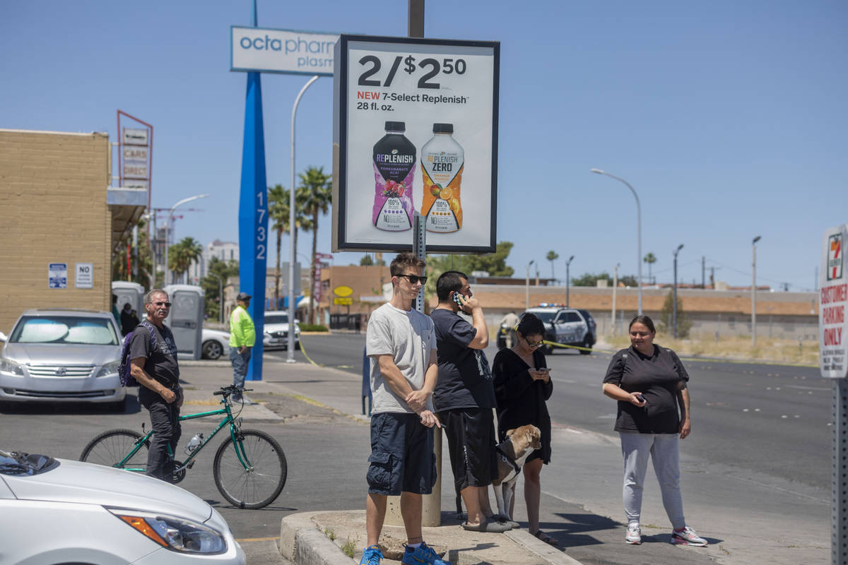 Individuals watch as the Las Vegas police investigate a downtown shooting in the 1900 block of ...