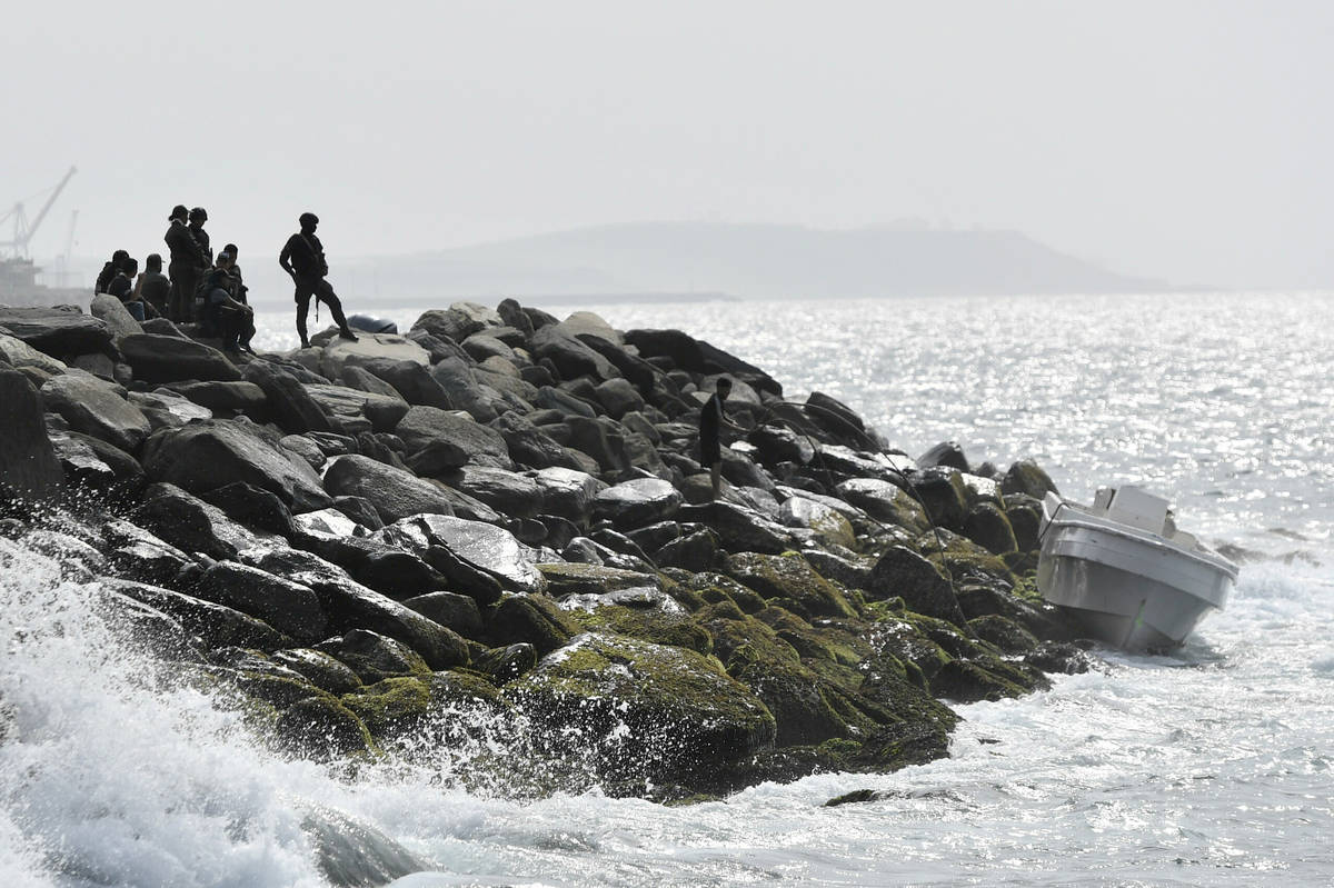 Security forces guard the shore area and a boat in which authorities claim a group of armed men ...