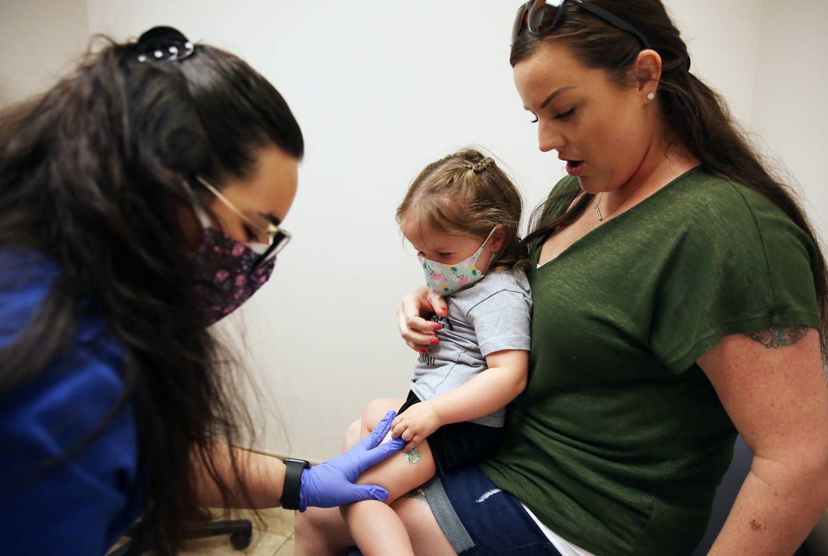 Olivia Hippert, 2, and her mother Amanda watch as Samantha Vizcaino, a medical assistant, appli ...