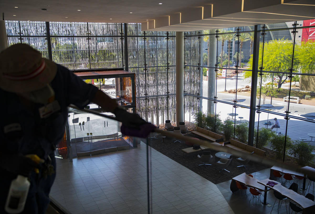 Custodian Jarrell Siler sanitizes handrails in the Hospitality Hall at UNLV in Las Vegas, Thurs ...