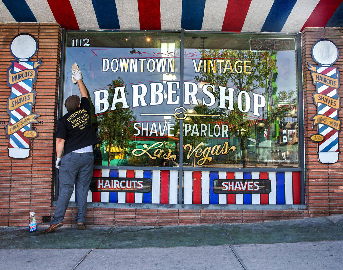 Jorge Reyes, owner of Downtown Vintage Barbershop, cleans his storefront in preparation to open ...