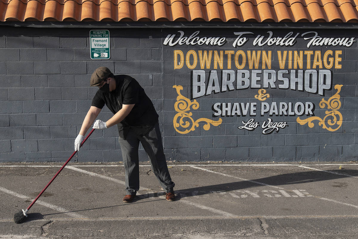Jorge Reyes, owner of Downtown Vintage Barbershop, sweeps in back of his business in preparatio ...