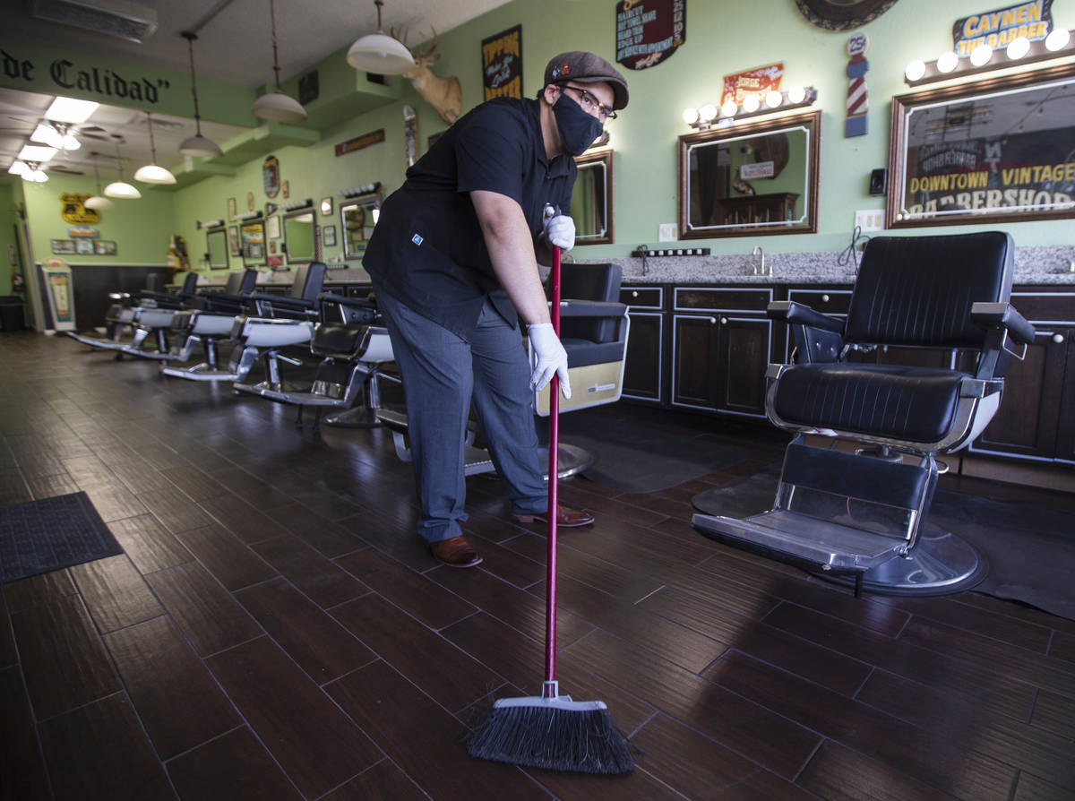 Jorge Reyes, owner of Downtown Vintage Barbershop, sweeps inside his business in preparation to ...