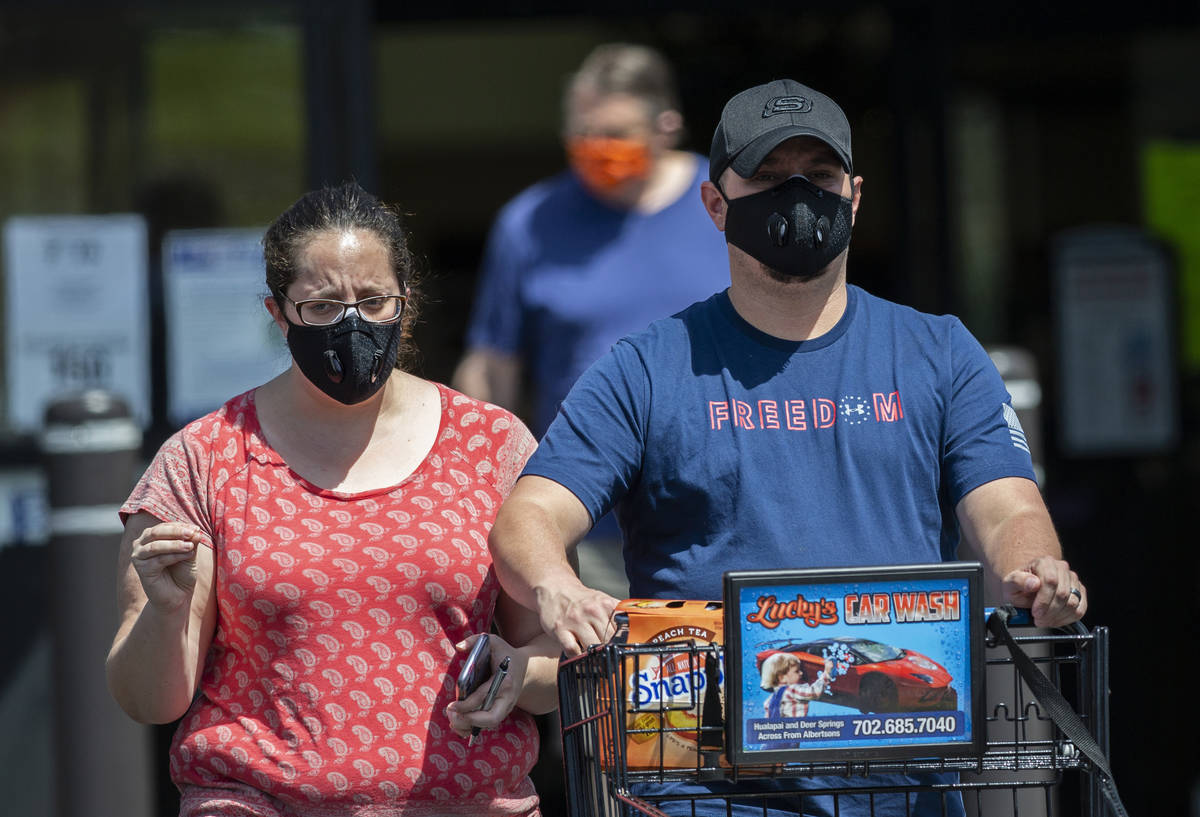 Shoppers wear protective masks as they leave Albertsons in northwest Las Vegas on Thursday, May ...
