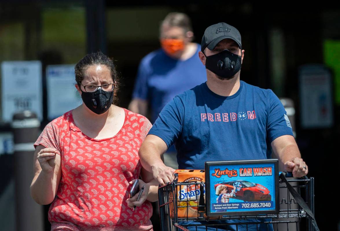 Shoppers wear protective masks as they leave Albertsons in northwest Las Vegas on Thursday, May ...