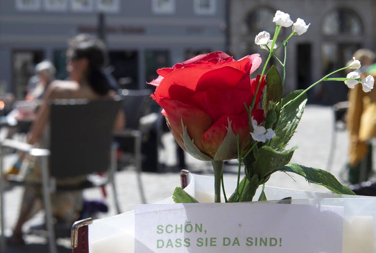 Restaurant guests relax behind a rose after the reopening of beer gardens in Weimar, central Ge ...