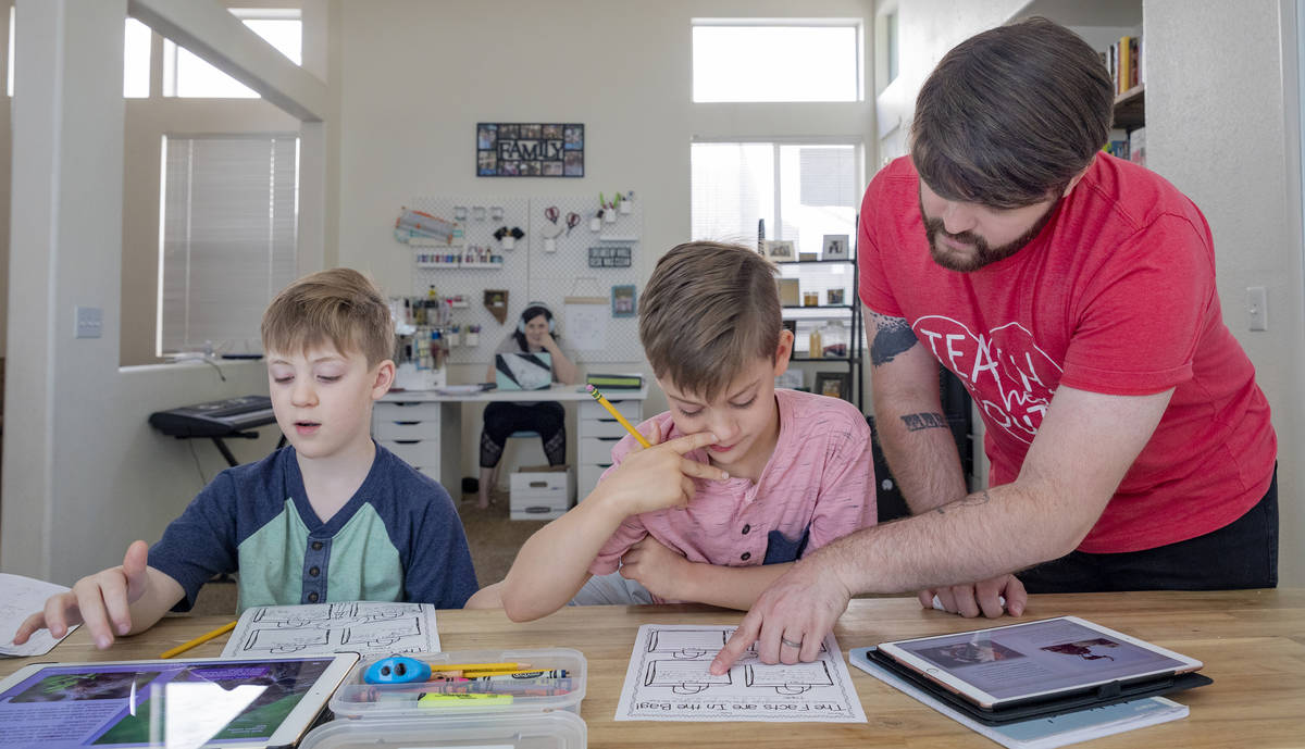 Twins Everett, left, and Atticus Mayville, 7, work on a school project with help from stepfathe ...