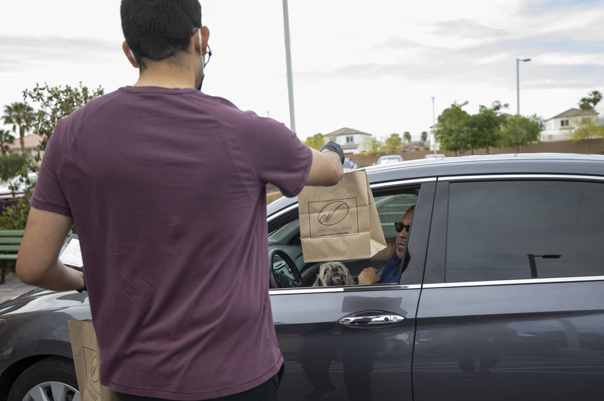 Anthony Campos hands Gil Jordan his curbside pickup order at Nora's Italian Cuisine on Wednesda ...