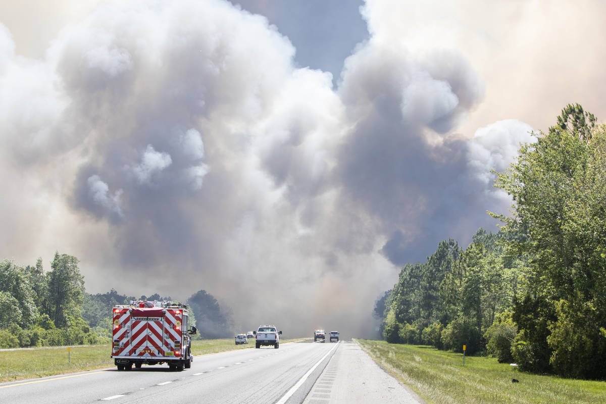 In this Wednesday, May 6, 2020 photo, emergency vehicles are stopped due to a large wildfire in ...